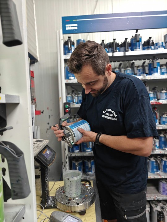 Medewerker met een blik verf in het verfmengstation